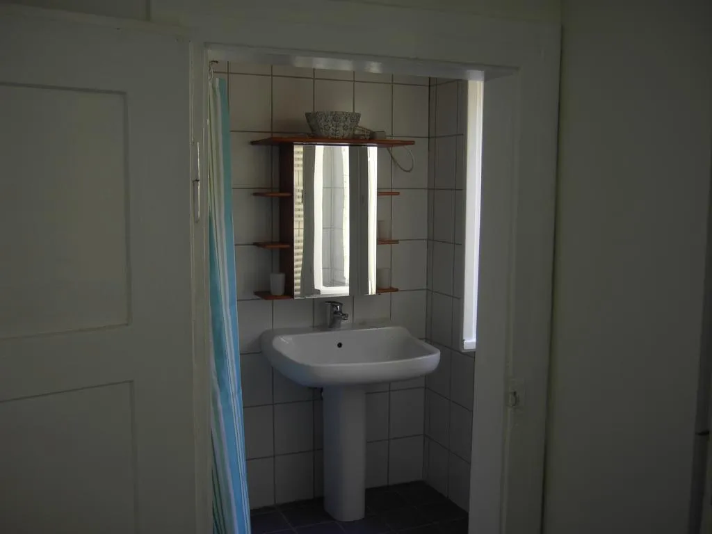 Das Bad mit Waschbecken, Spiegel und Dusche hinter dem Vorhang.