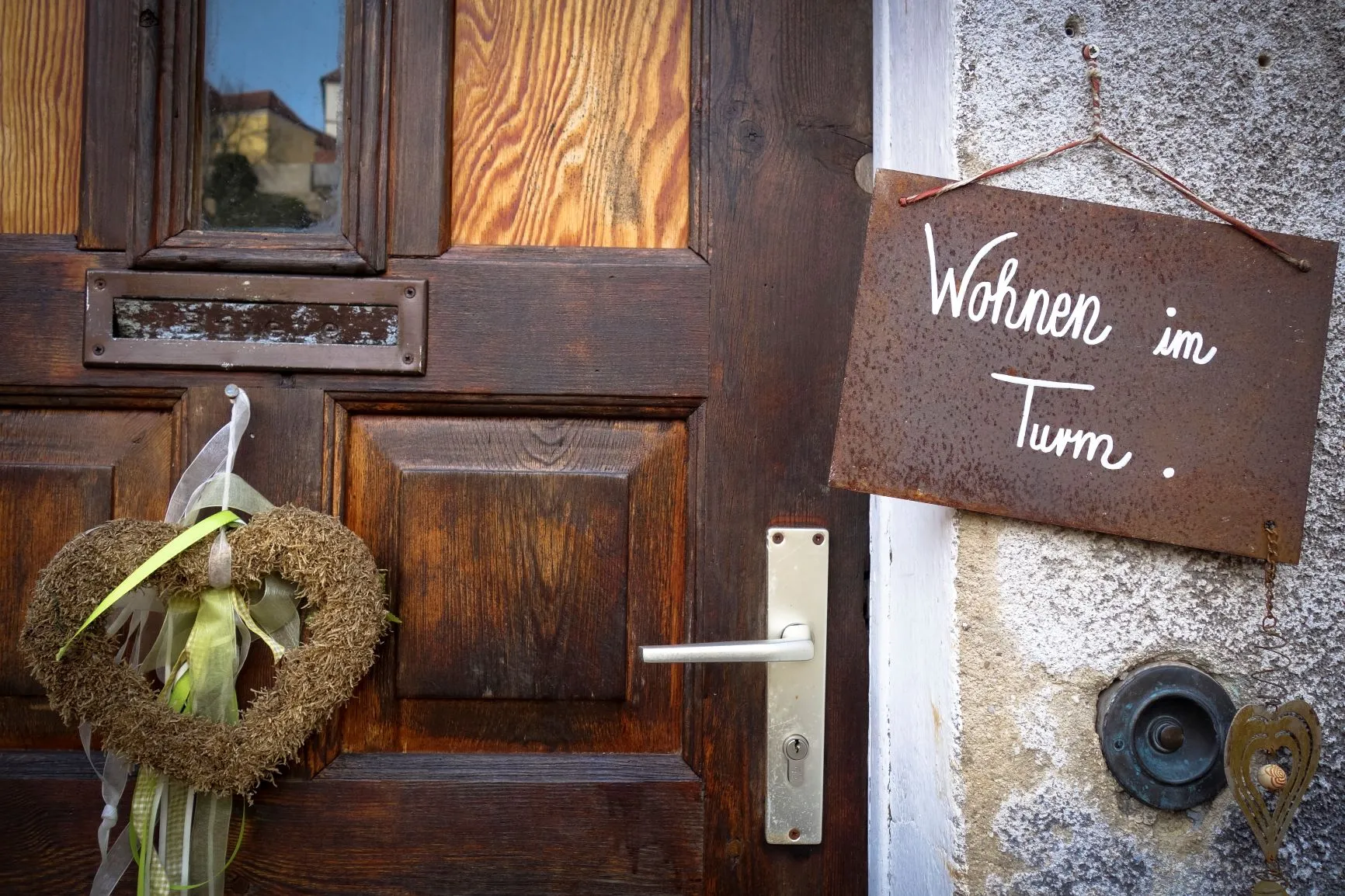 Die Haustür mit dem Schild „Wohnen im Turm.“ und einem Moosherz am Türblatt.